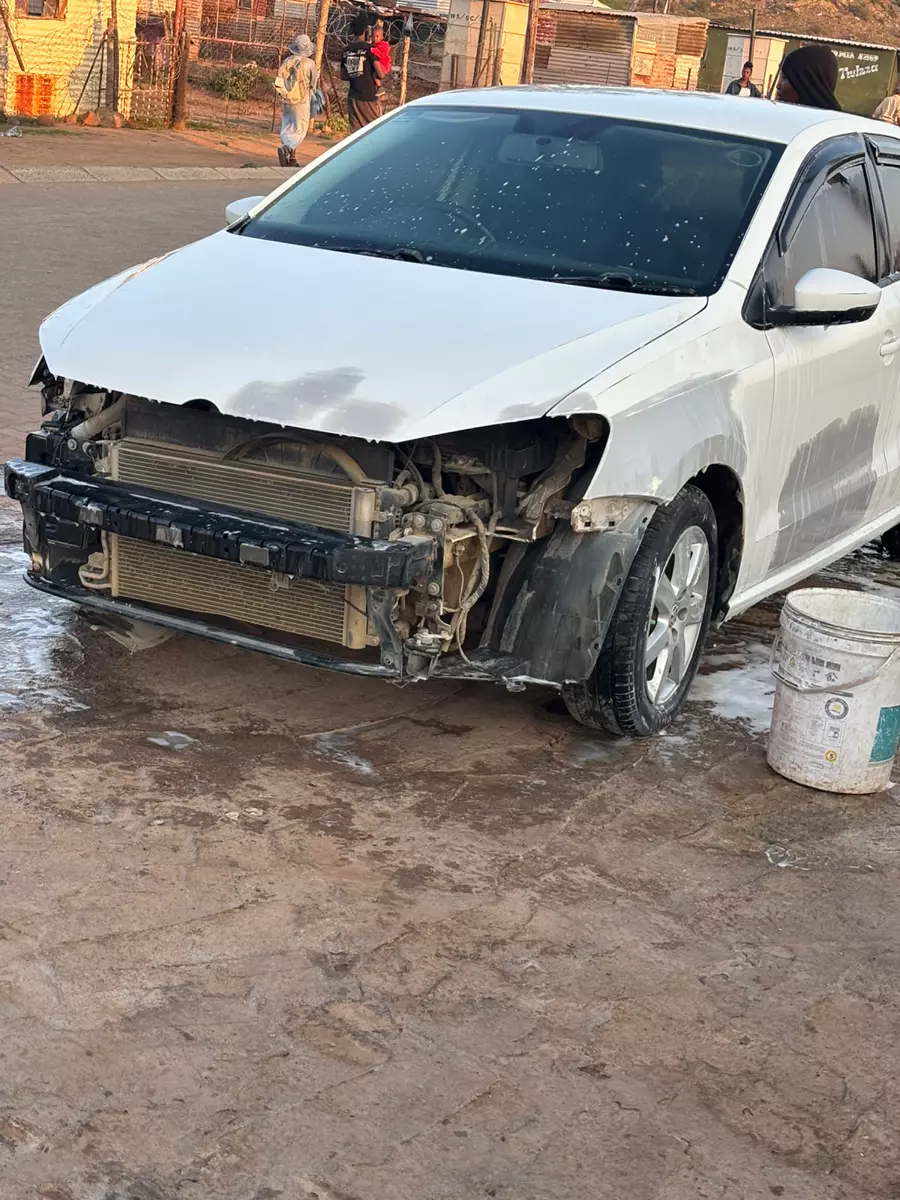 A white car with front-end damage before repairs